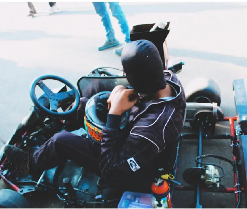 A driver helmet and gloved hands on the steering wheel, seen from behind.